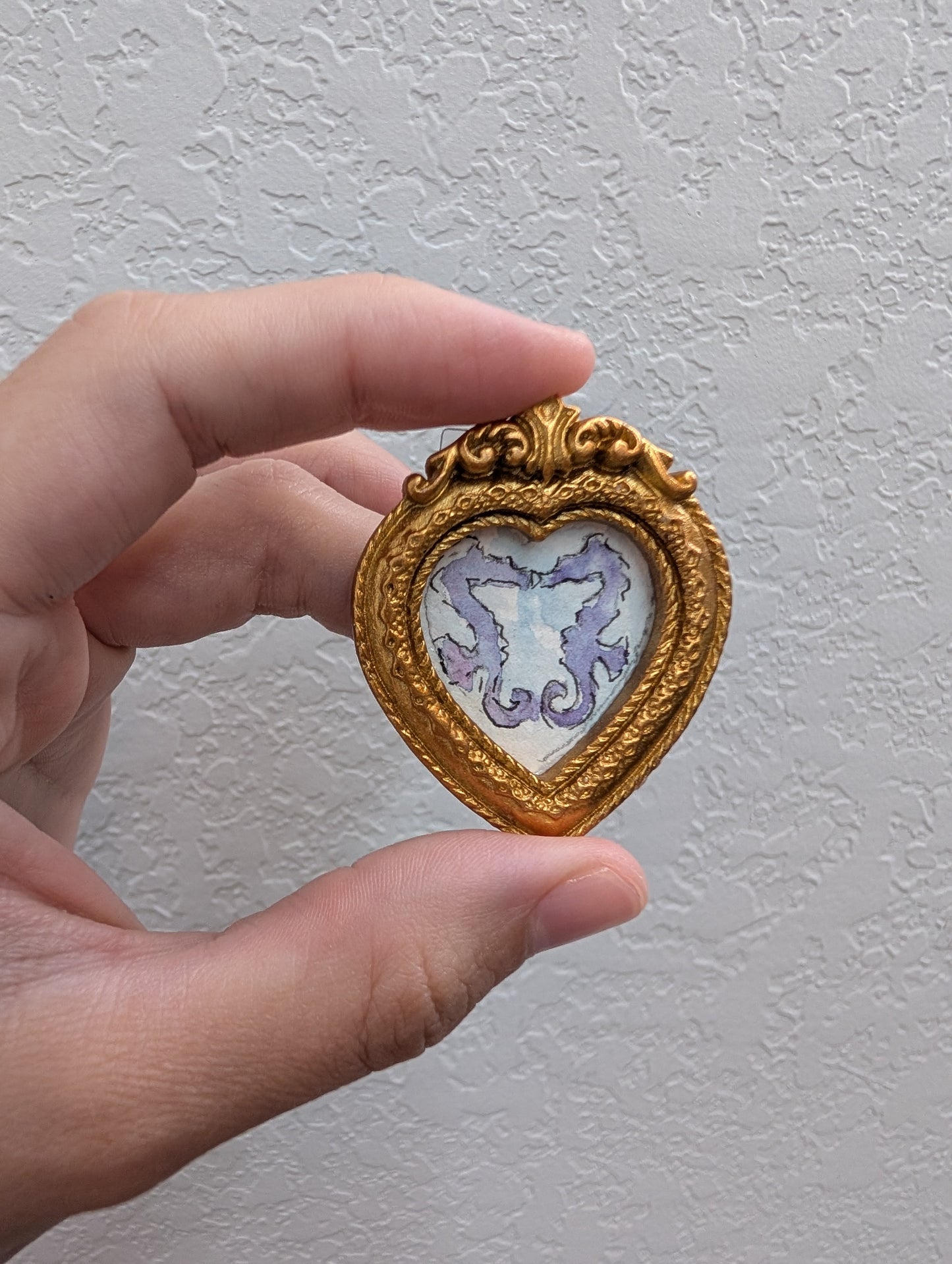 a hand holding a miniature heart shaped picture frame