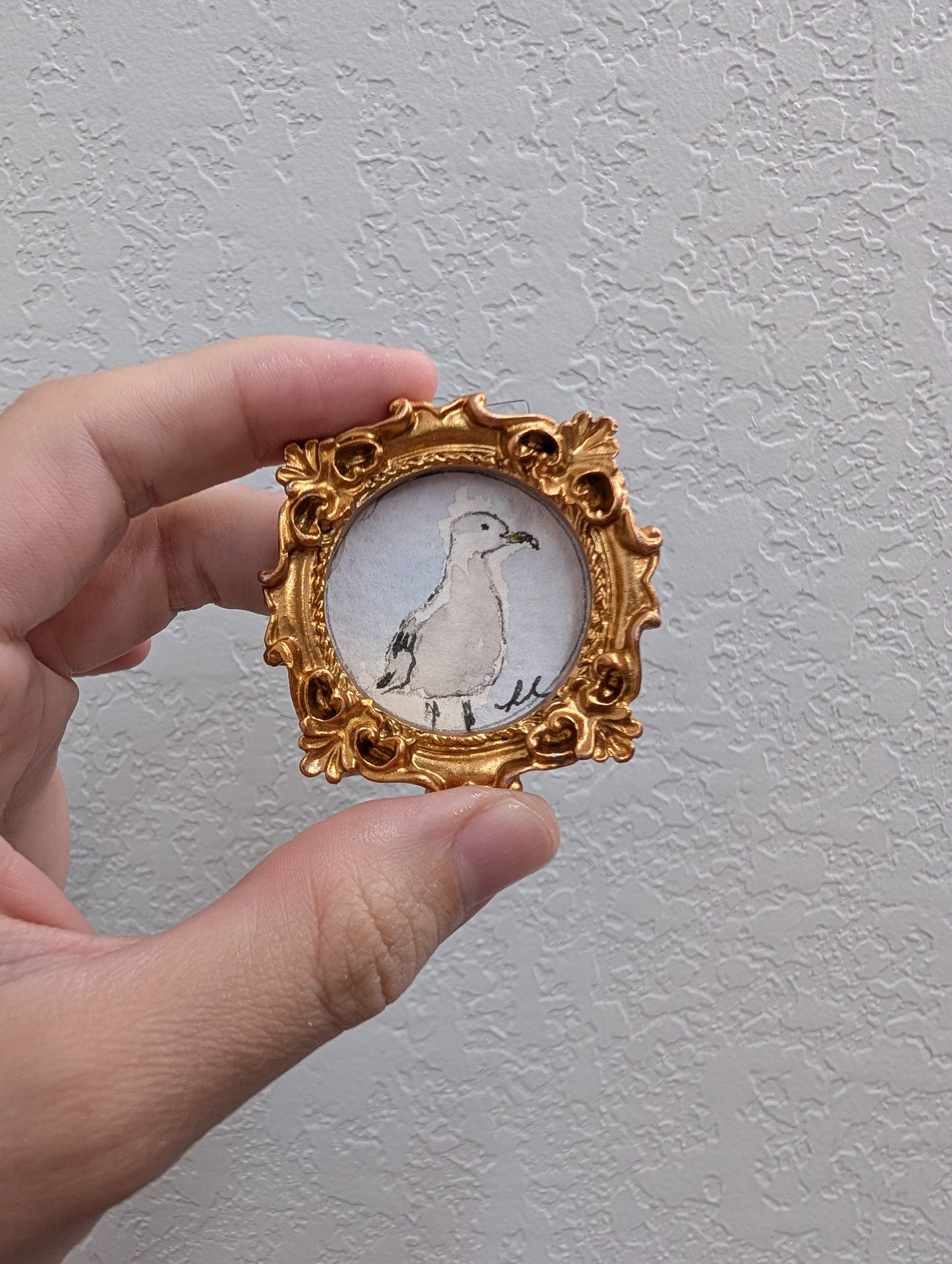 a hand holding a miniature picture of a bird