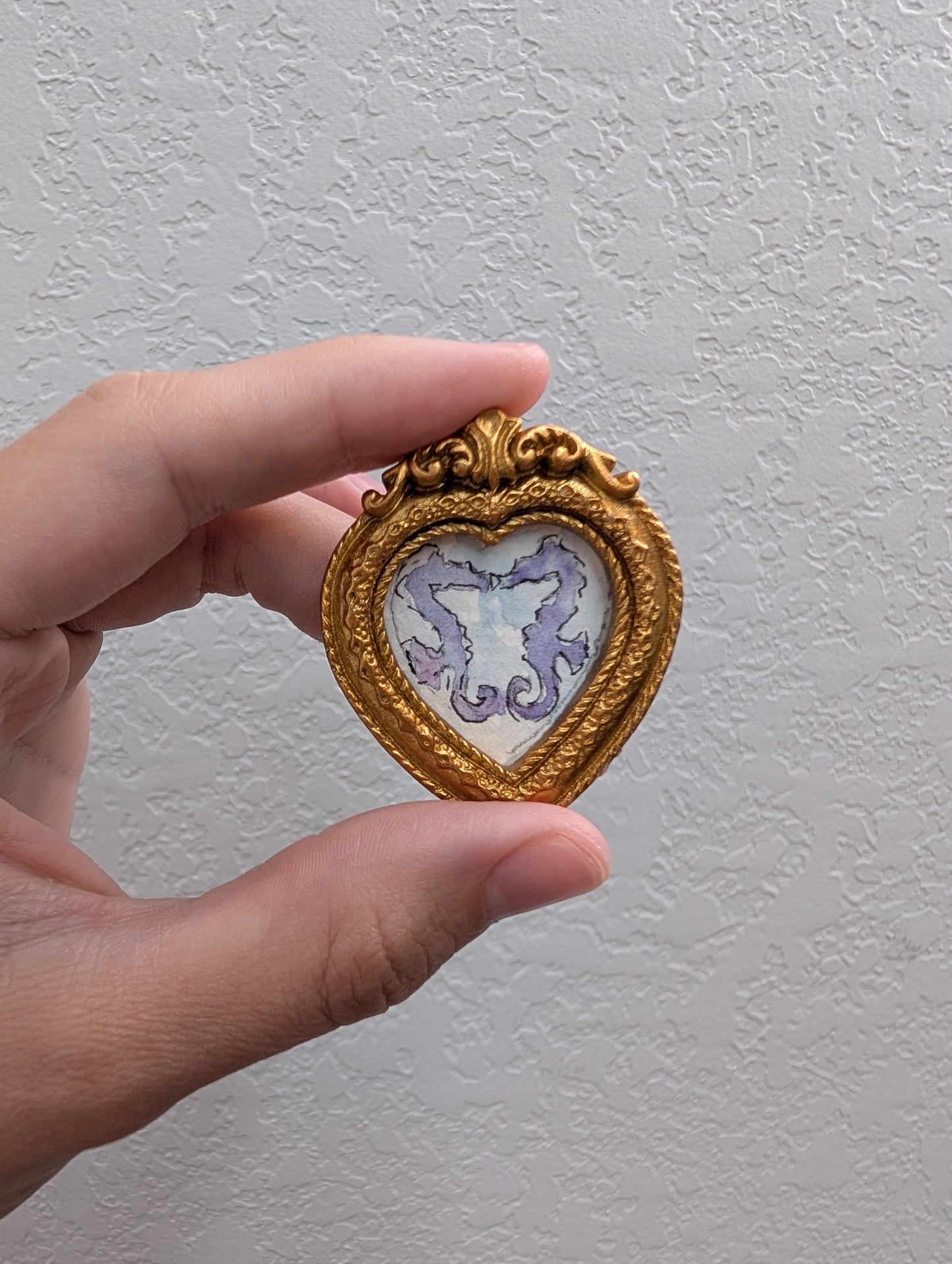 a hand holding a miniature picture frame in it's palm