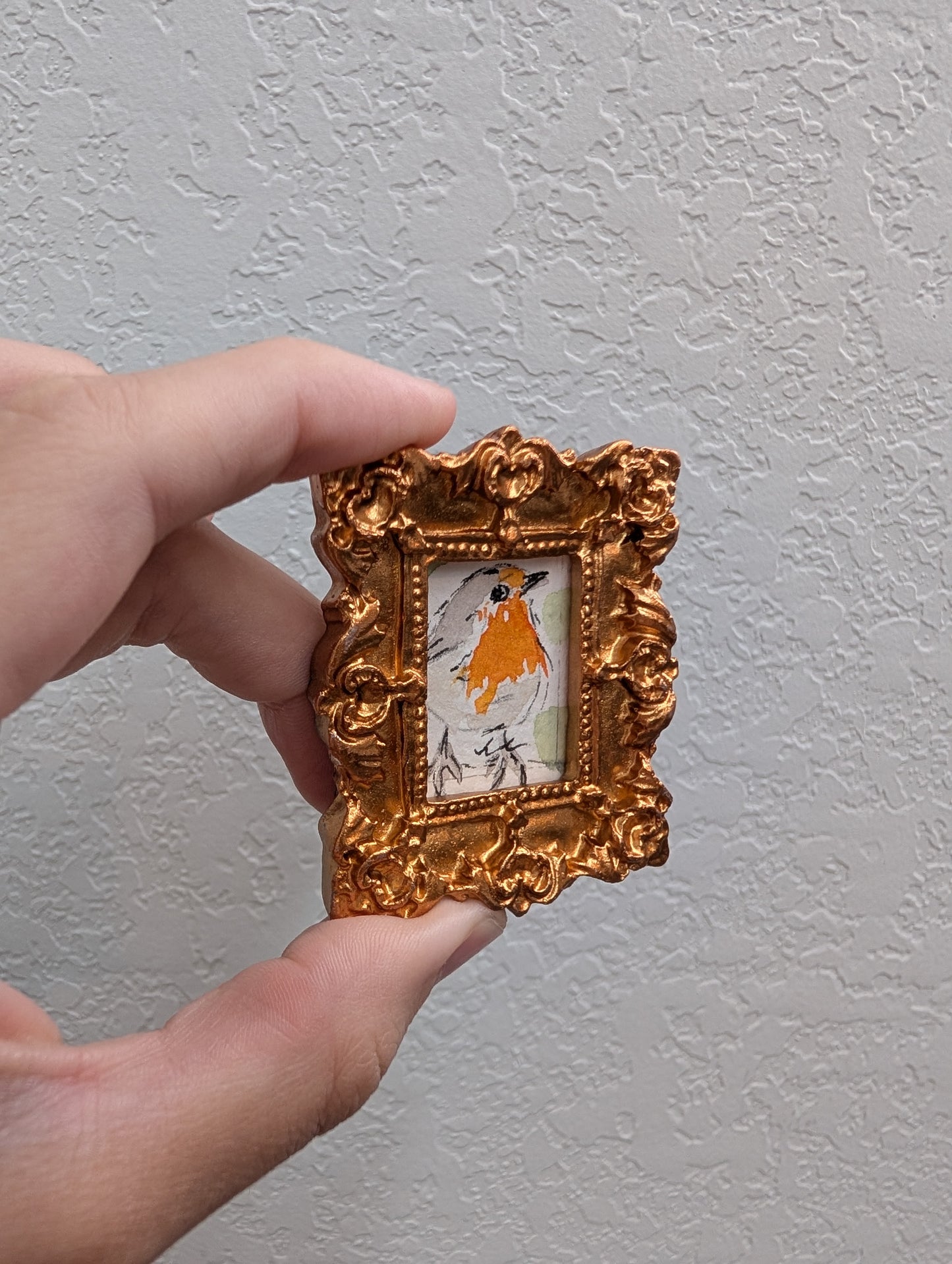a hand holding a small picture frame with a picture of a woman