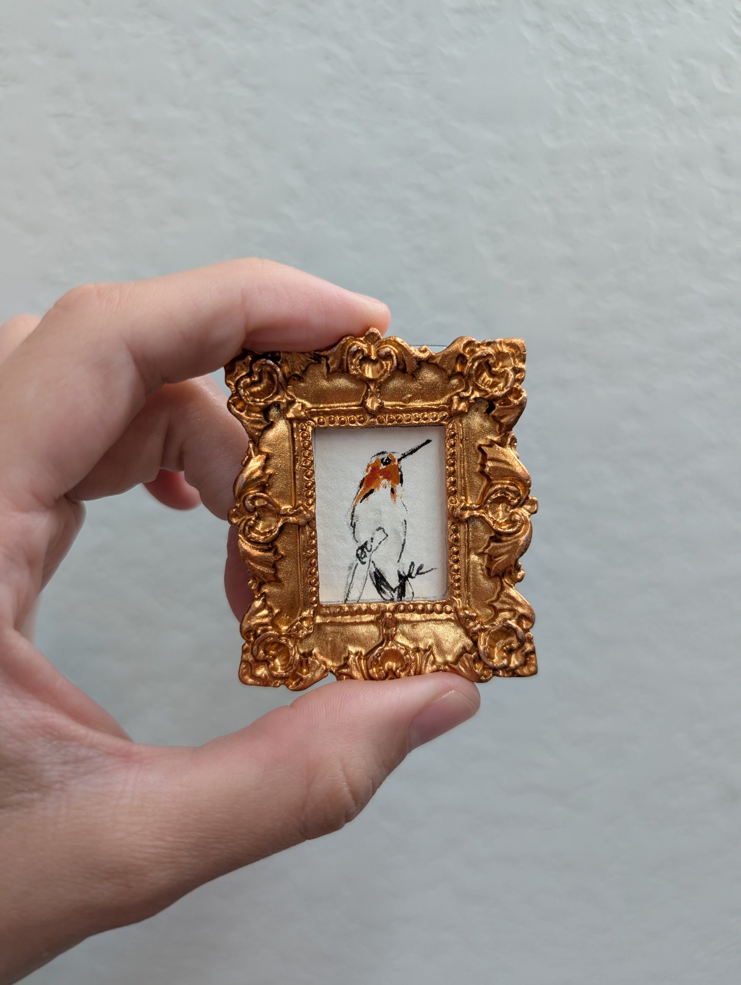 a person holding a small picture frame with a bird on it