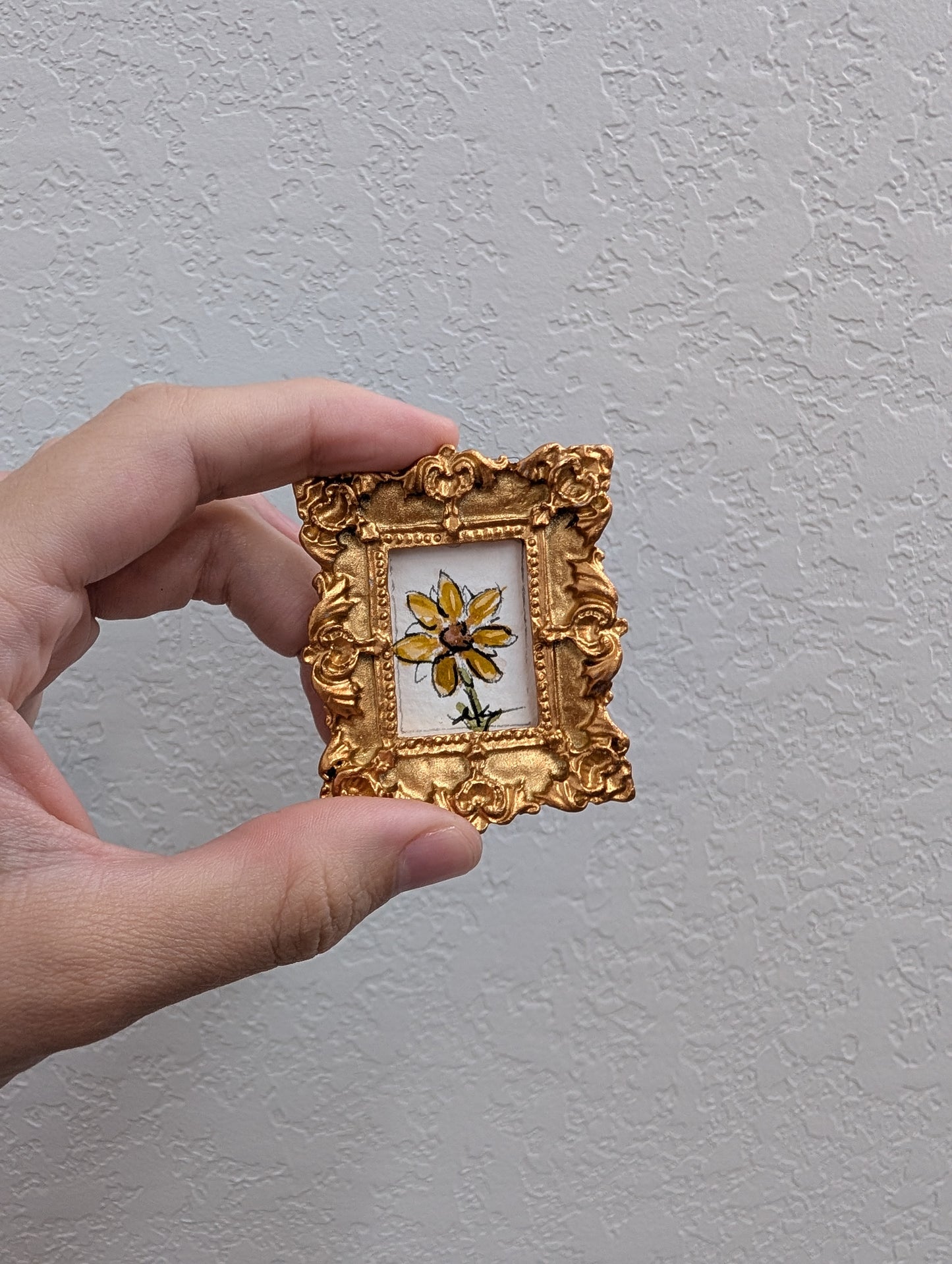 a person holding a small picture frame with a flower on it