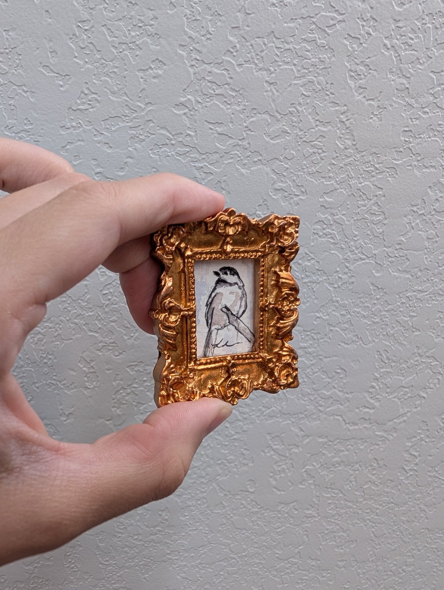 a person holding a small picture frame with a bird on it