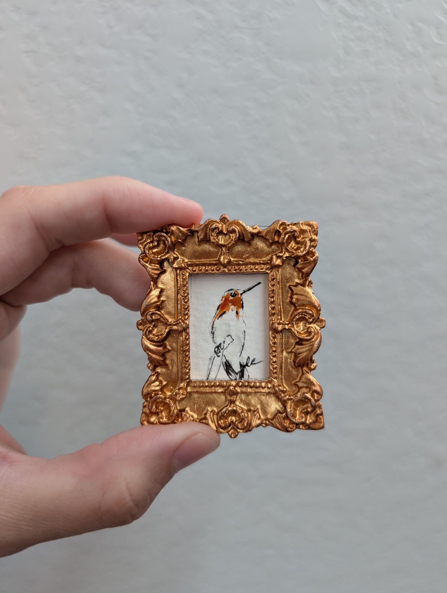 a person holding a small picture frame with a bird on it