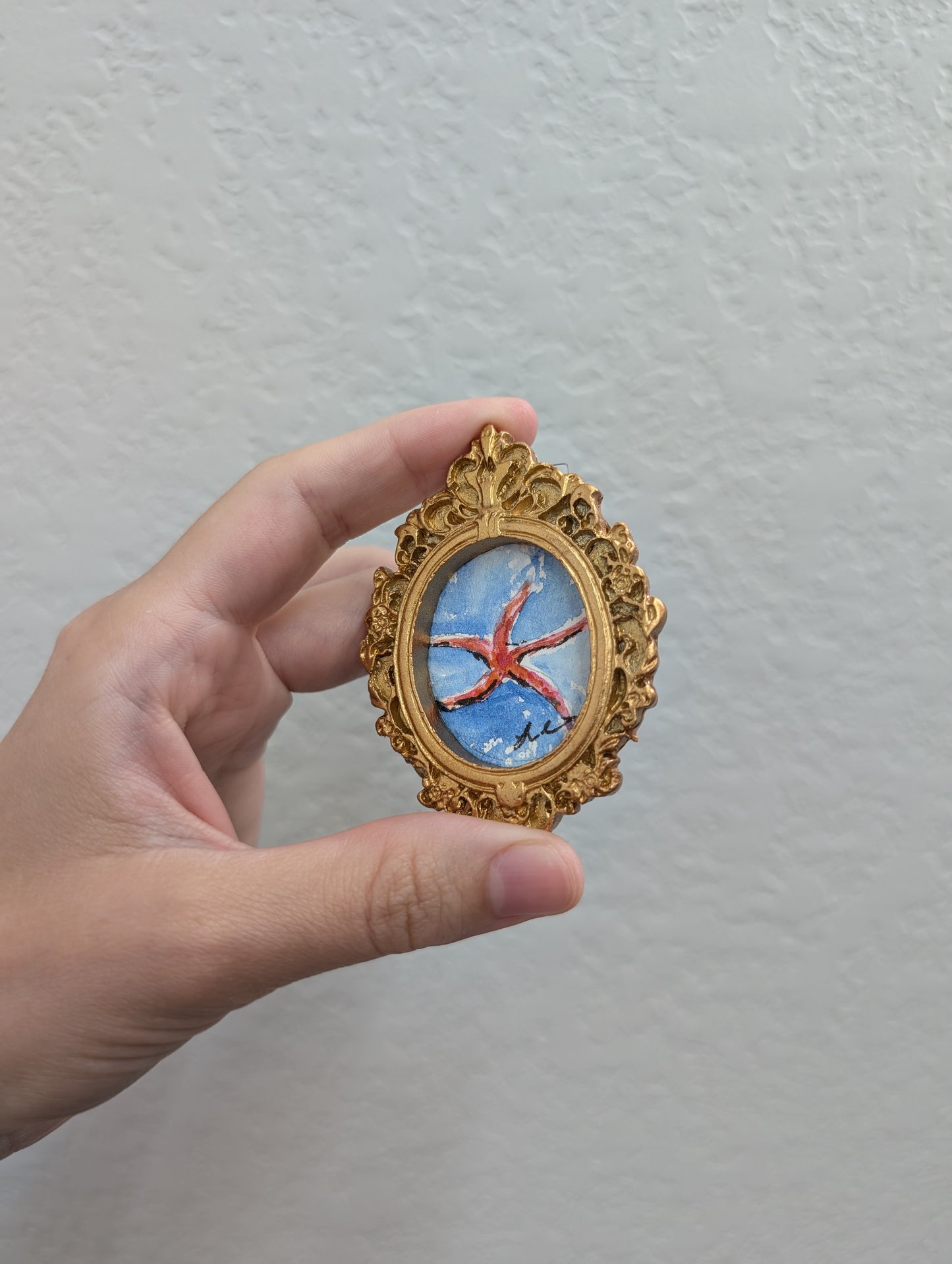 a hand holding a miniature picture of a bird