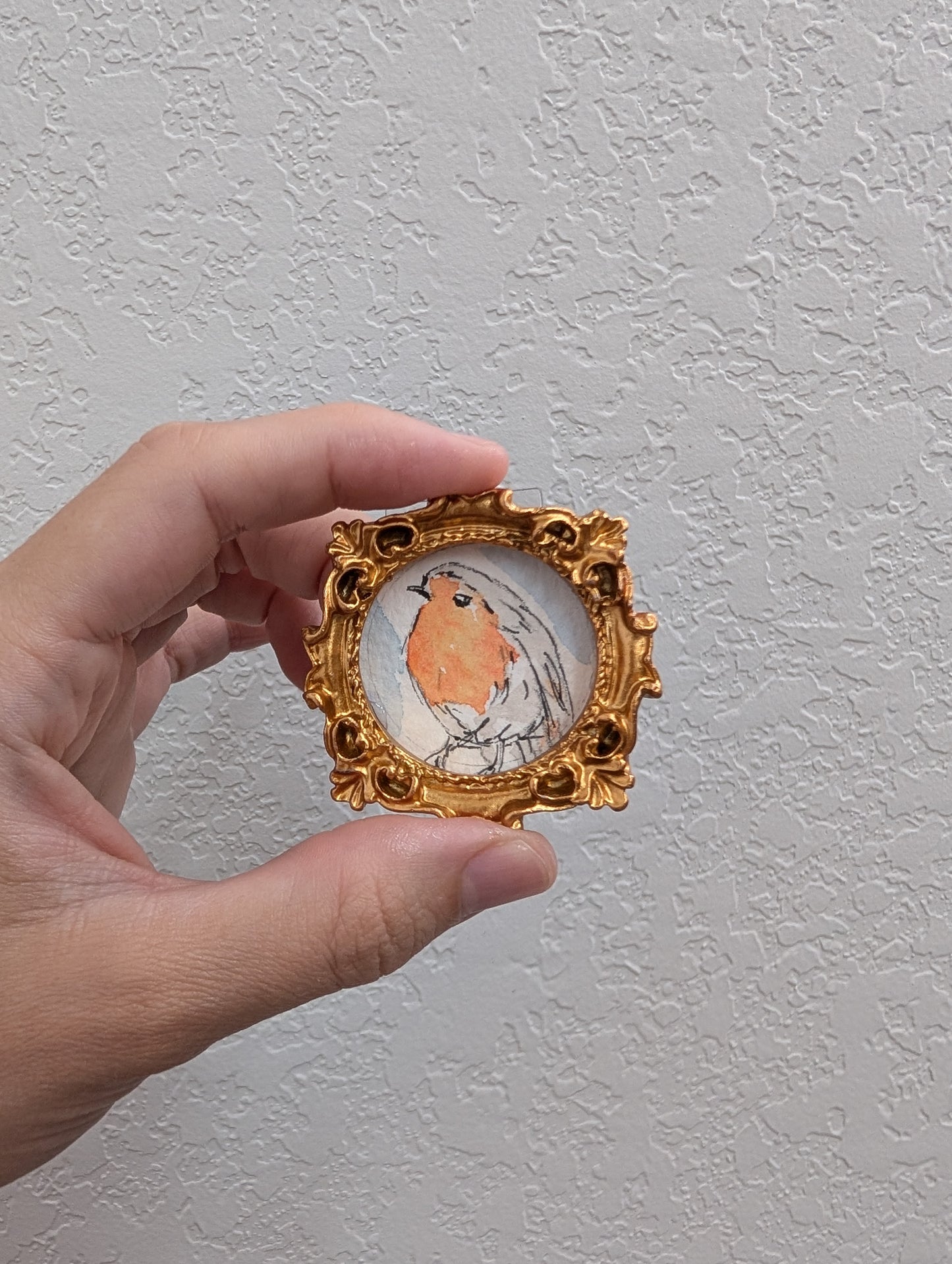 a hand holding a miniature picture of a bird
