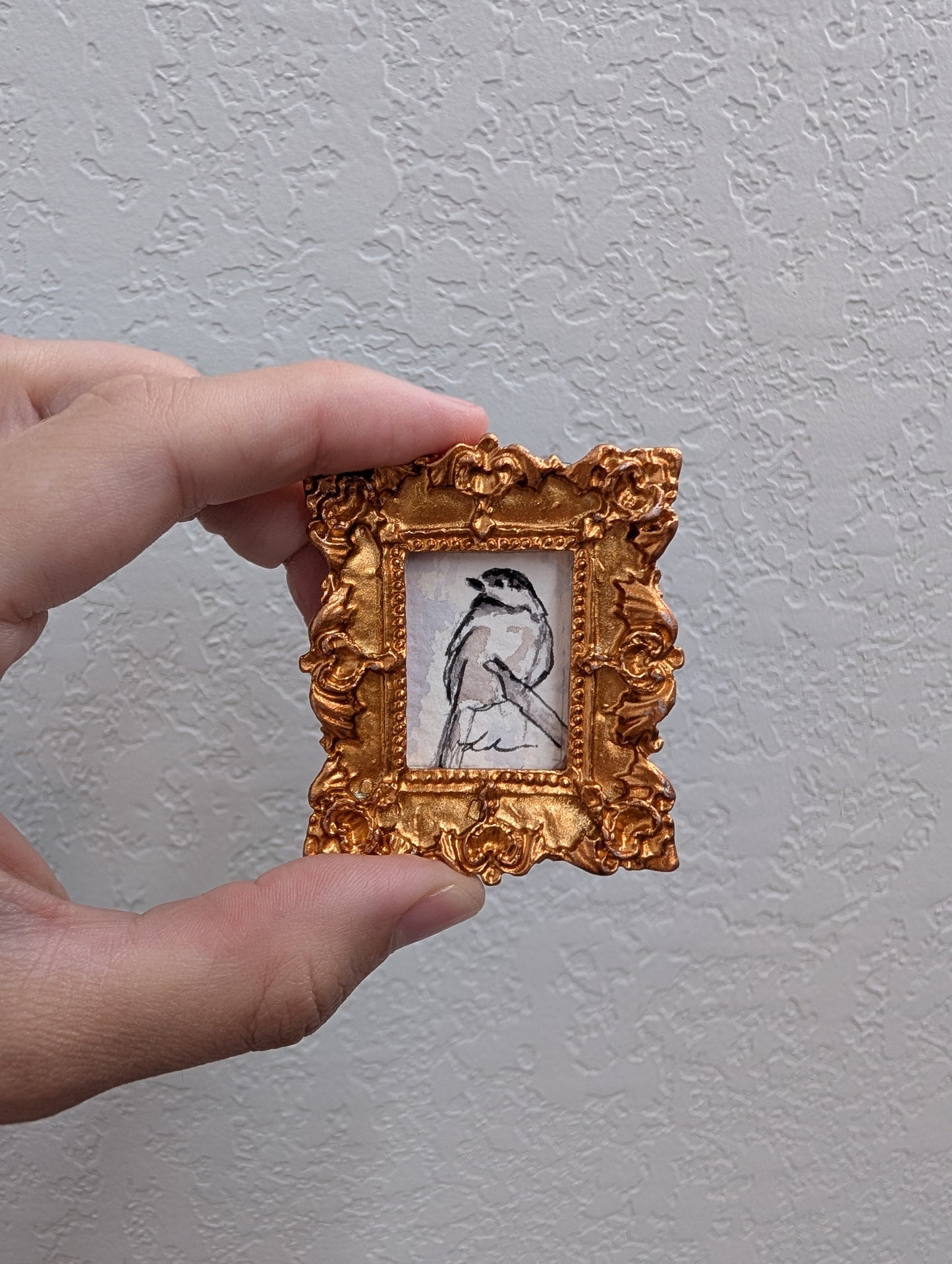 a person holding a small picture frame with a bird on it