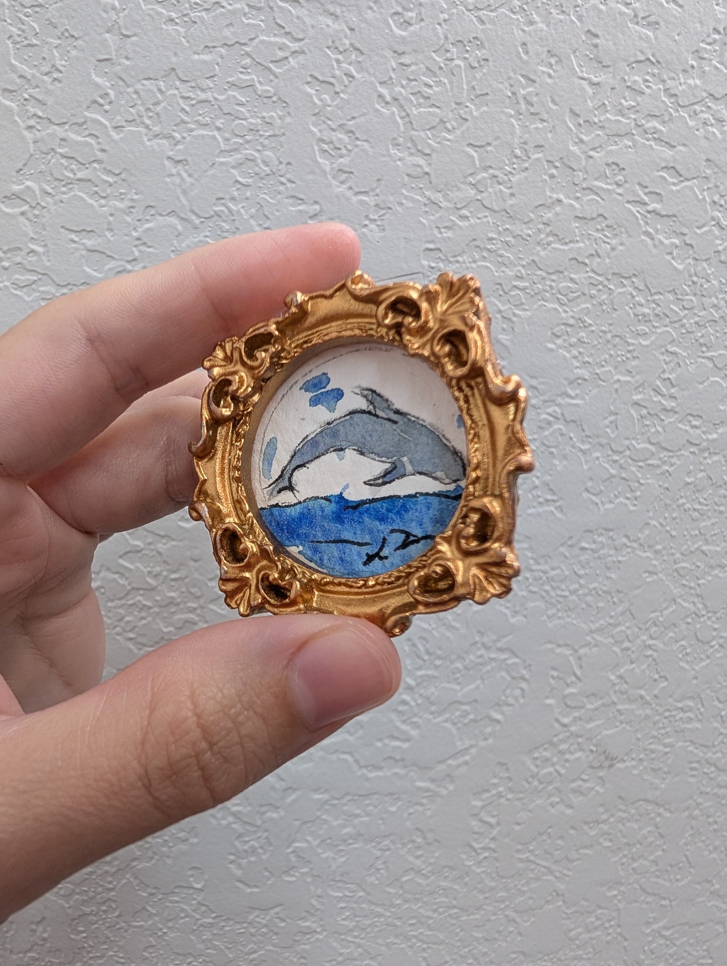a hand holding a picture frame with a dolphin on it