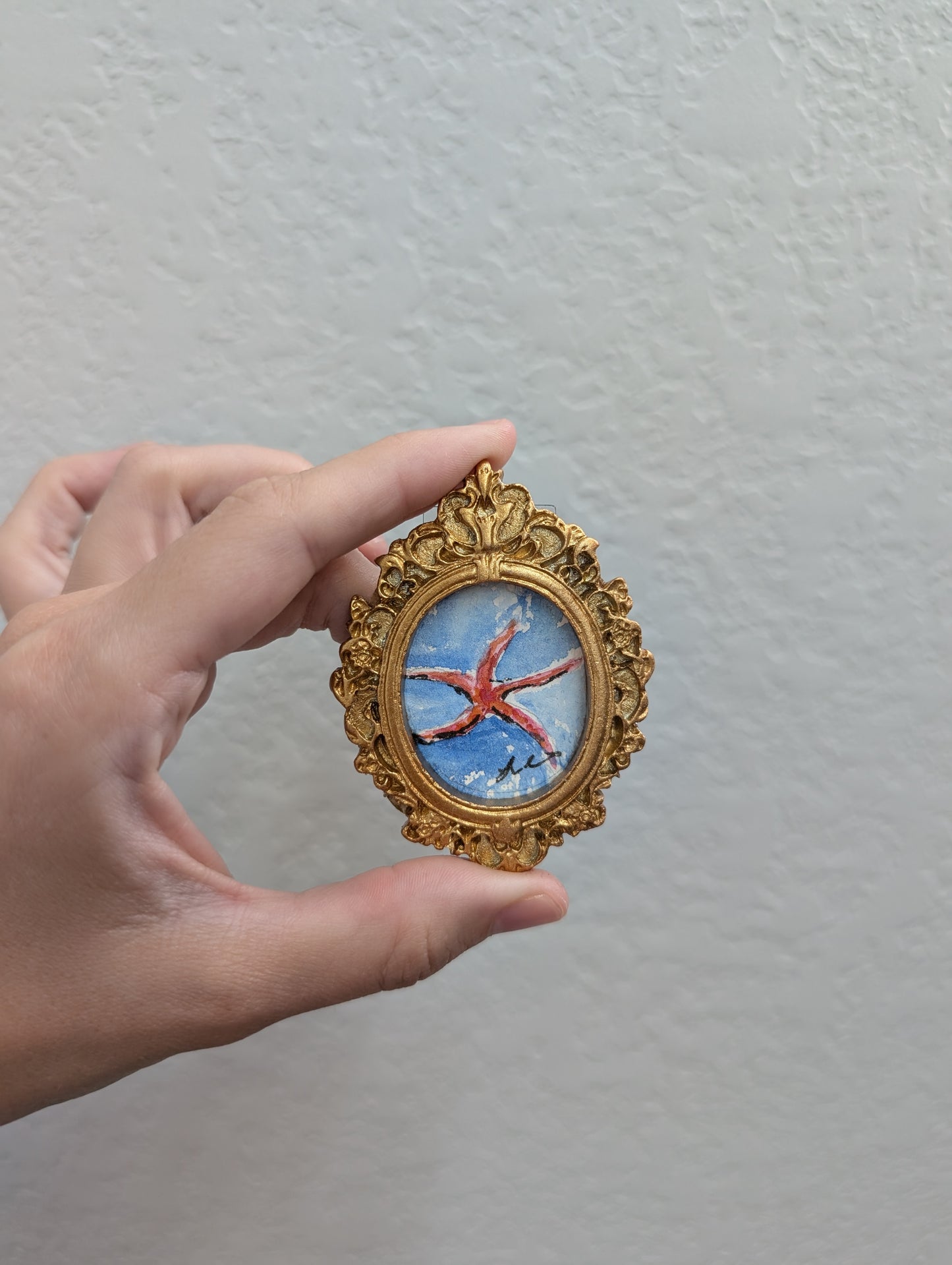 a hand holding a miniature picture of a starfish