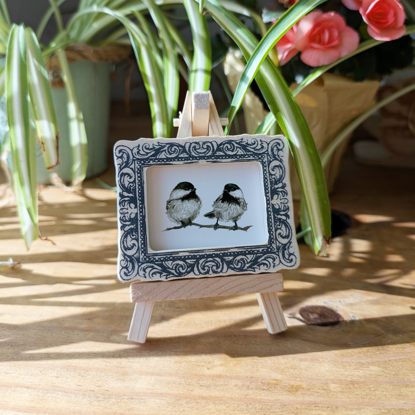a picture of two birds sitting on a small easel