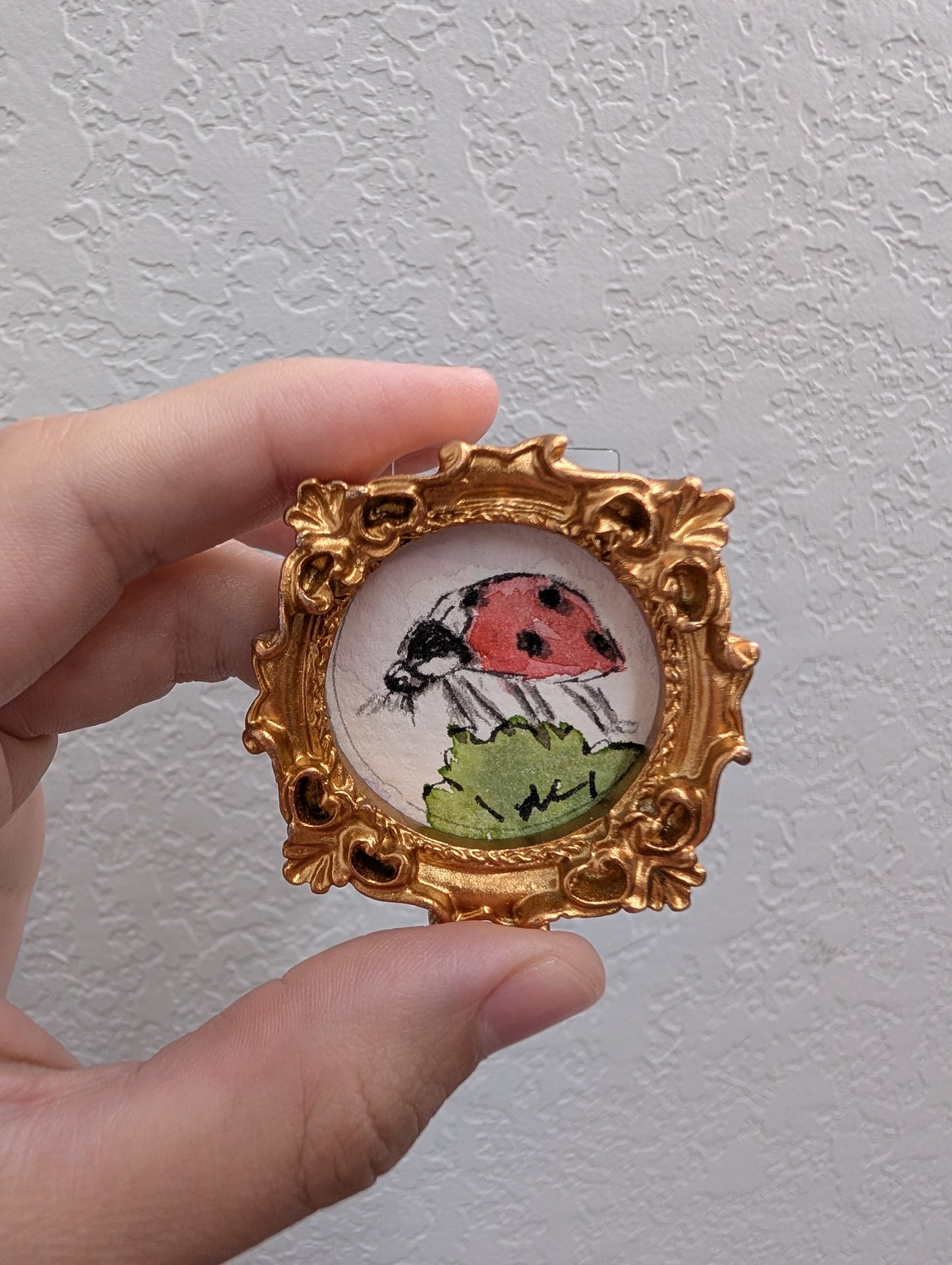 a hand holding a small picture frame with a bird on it