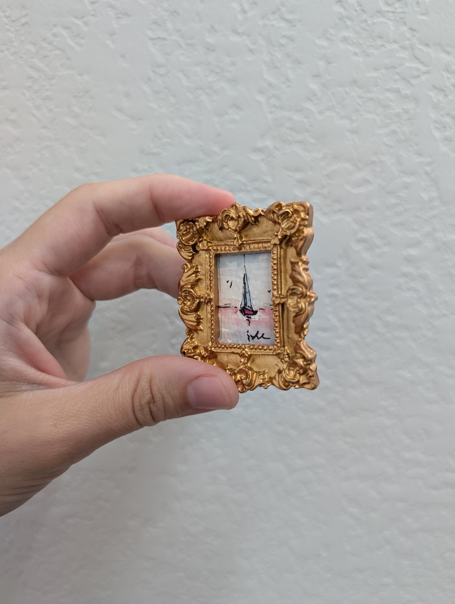 a person holding a small picture frame with a picture of a boat in it