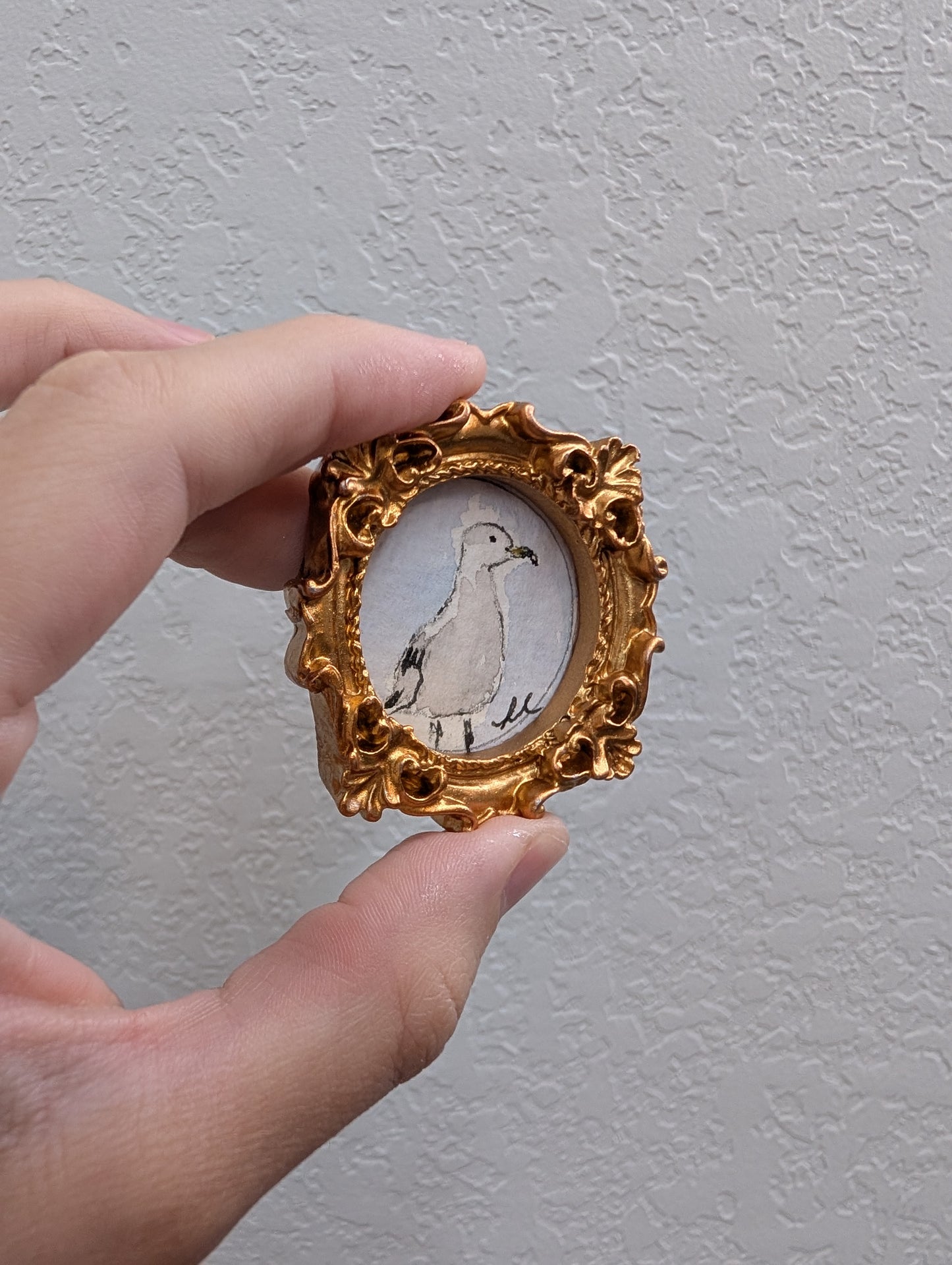 a hand holding a miniature picture of a bird