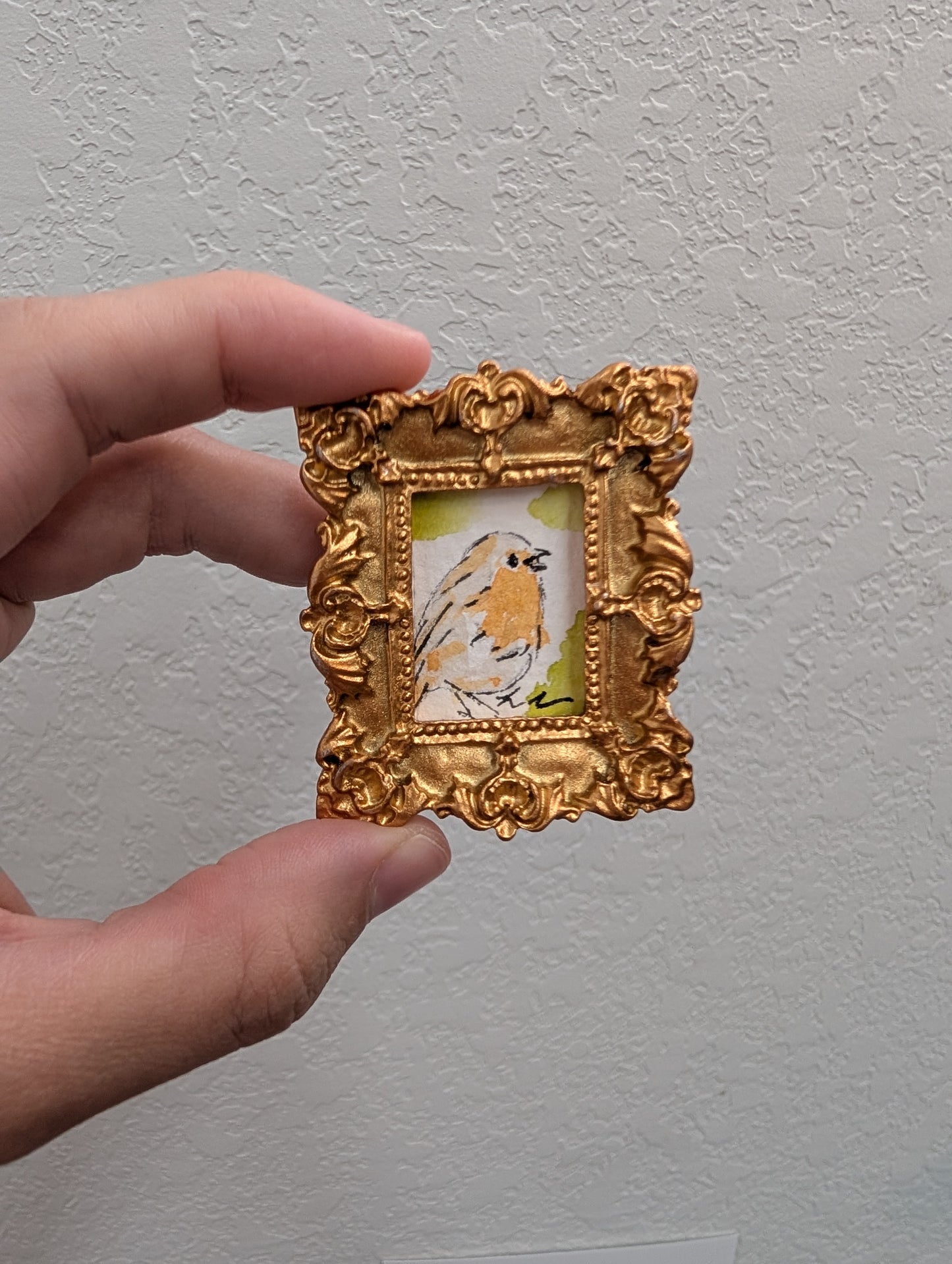 a person holding a small picture frame with a bird on it