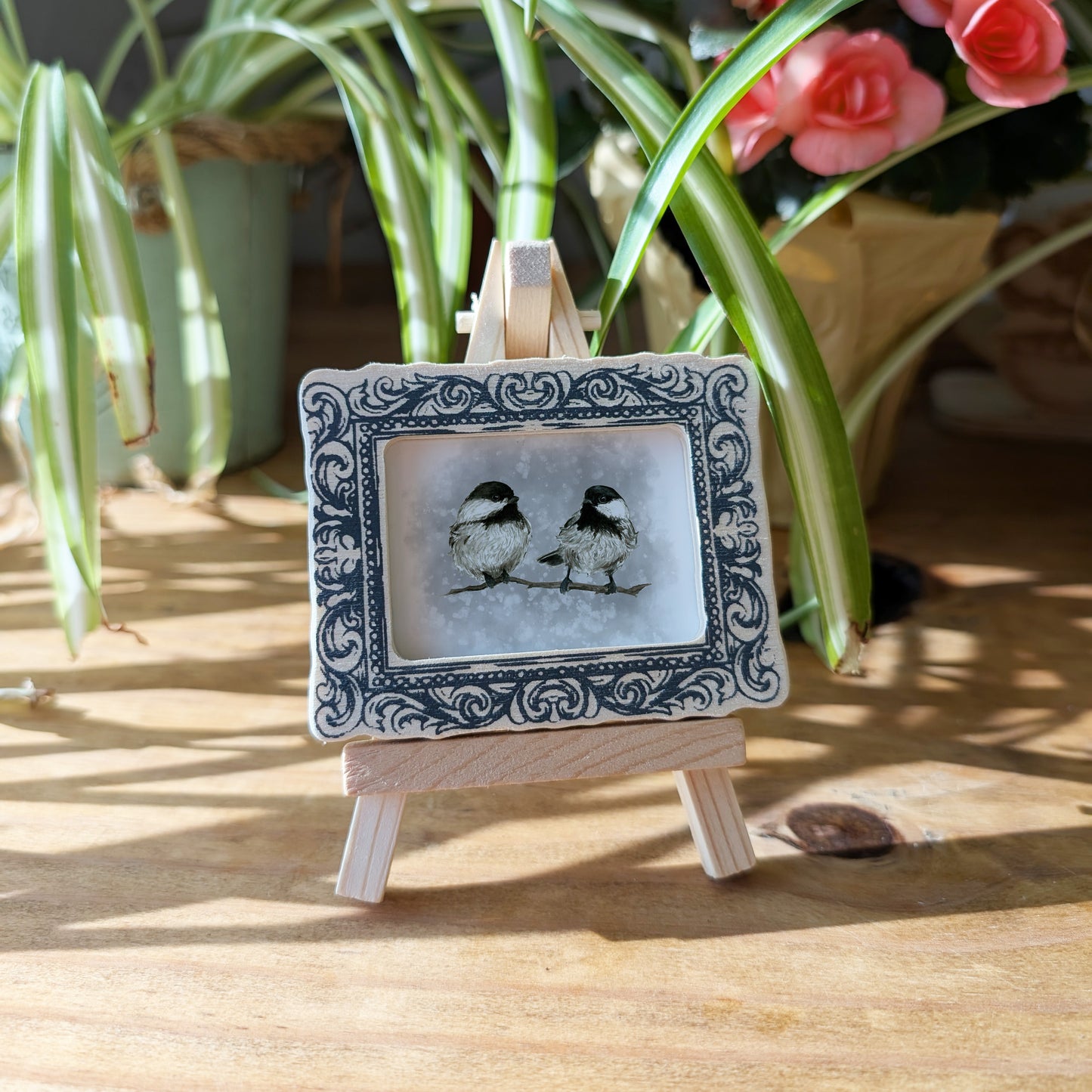 a picture of two birds sitting on top of a wooden easel