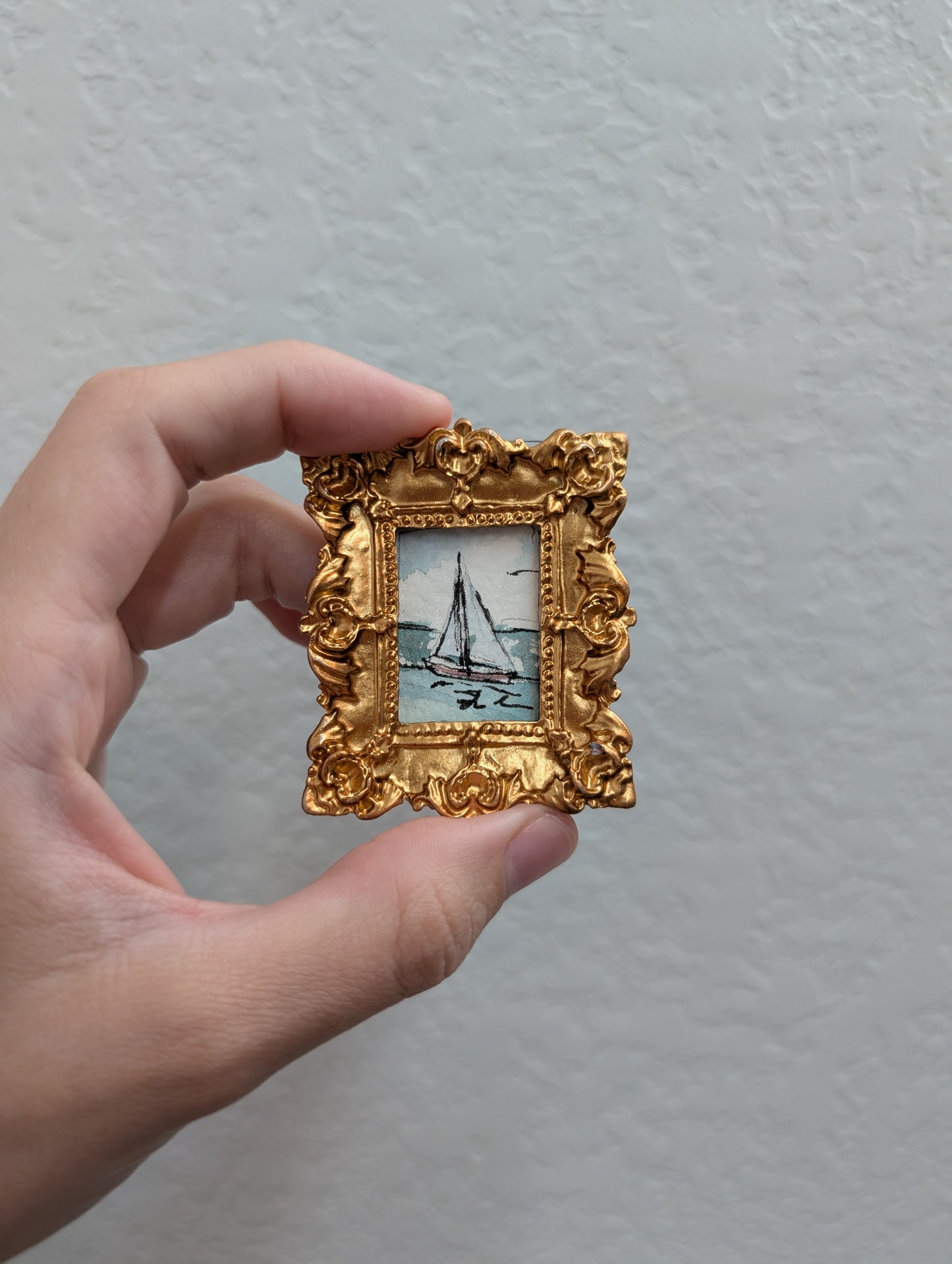 a person holding a small picture frame with a boat on it