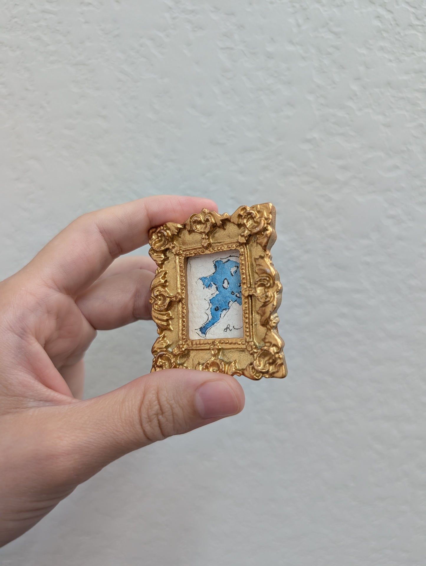 a person holding a small picture frame with a picture of a cat in it