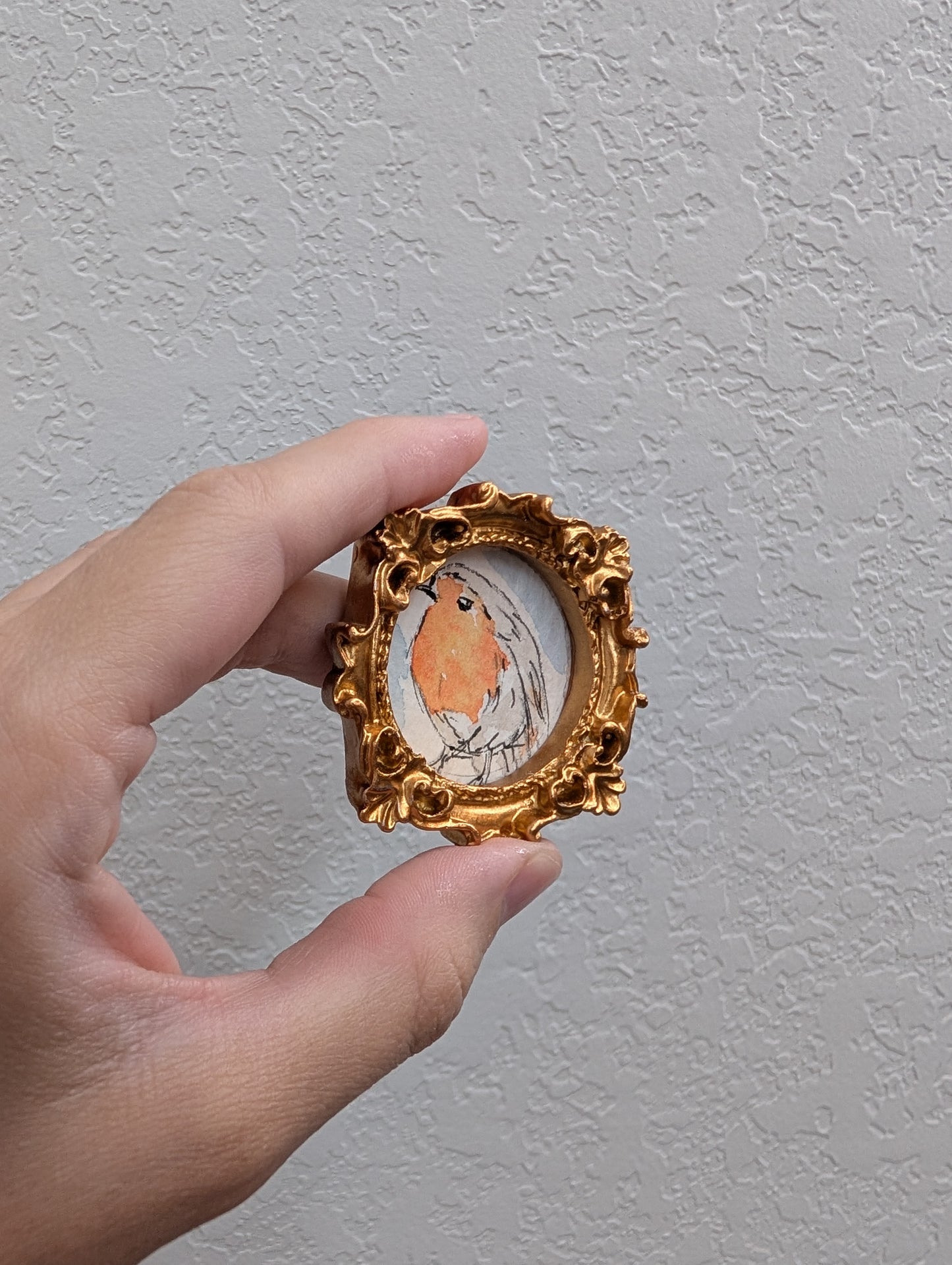a hand holding a miniature picture of a bird