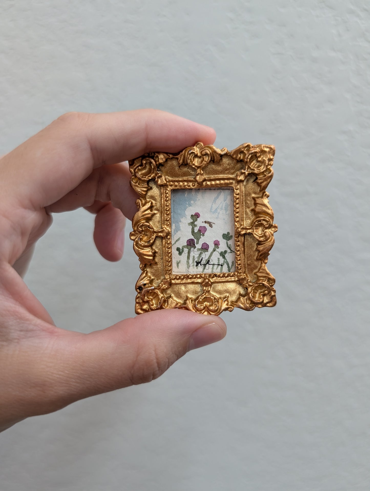 a person holding a small picture frame with flowers on it