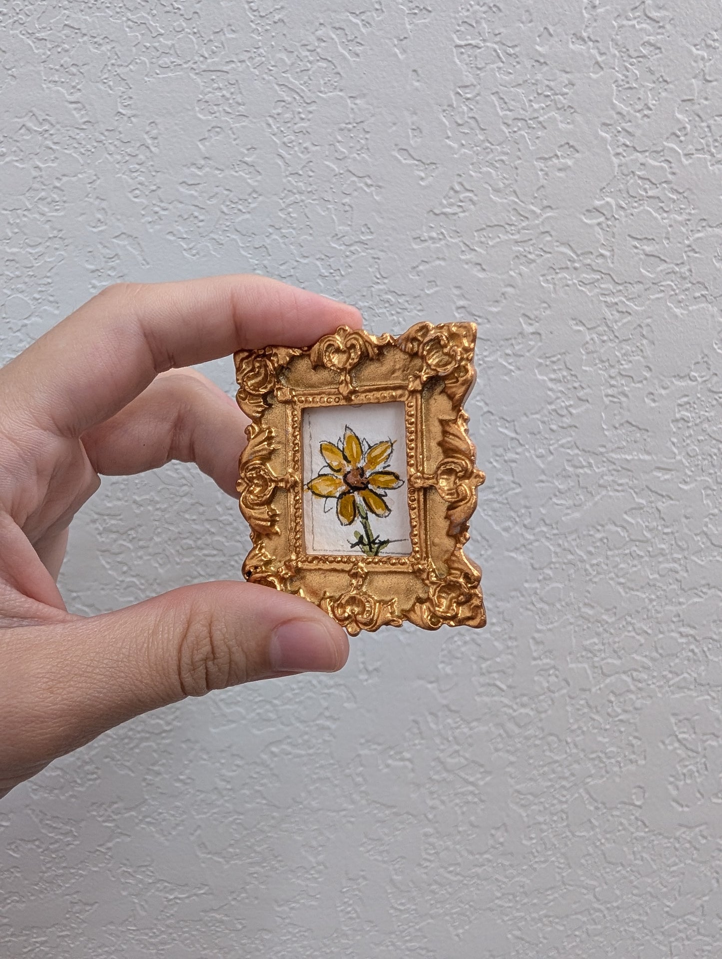 a person holding a small picture frame with a flower on it