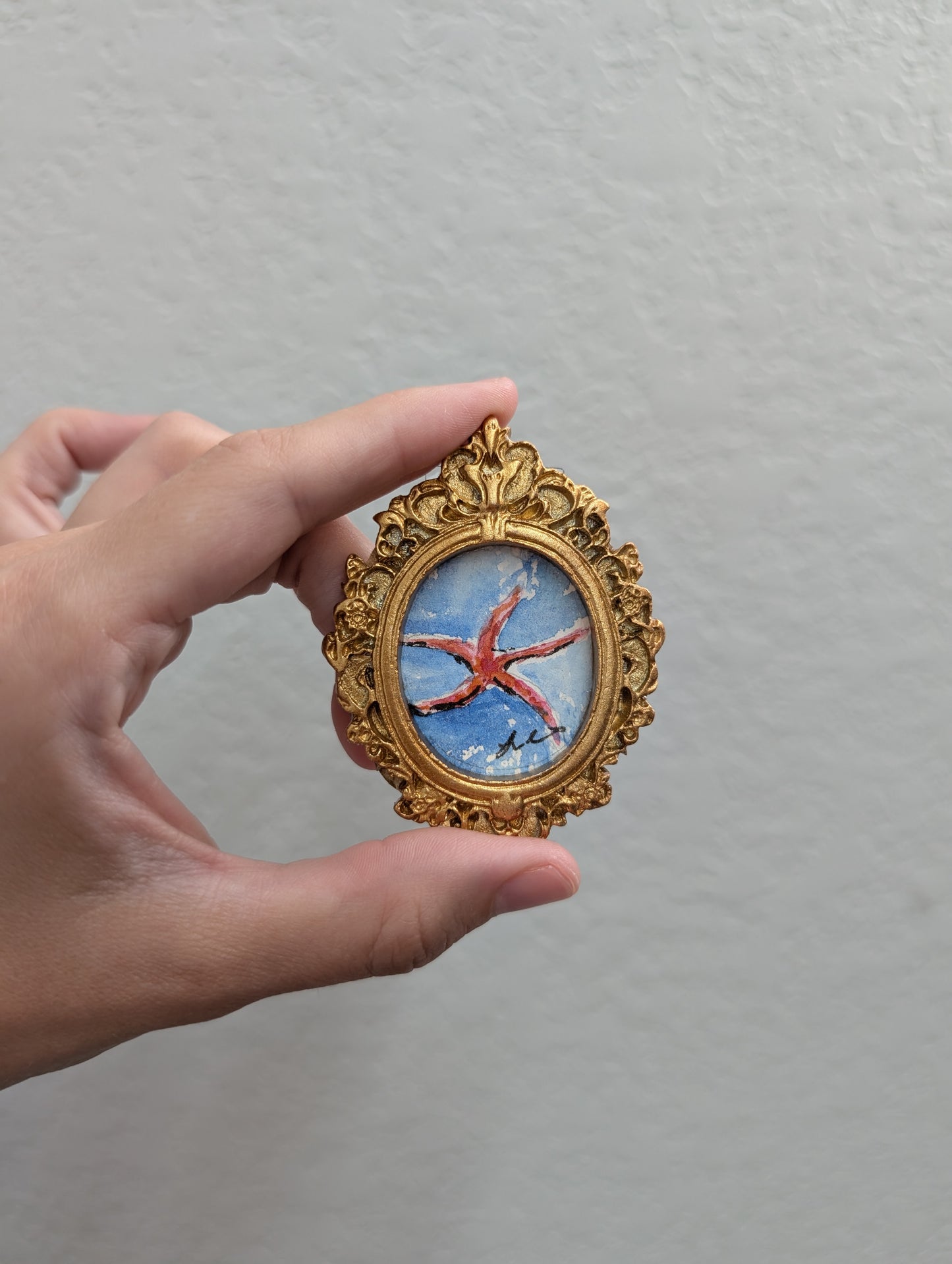 a hand holding a miniature picture of a bird