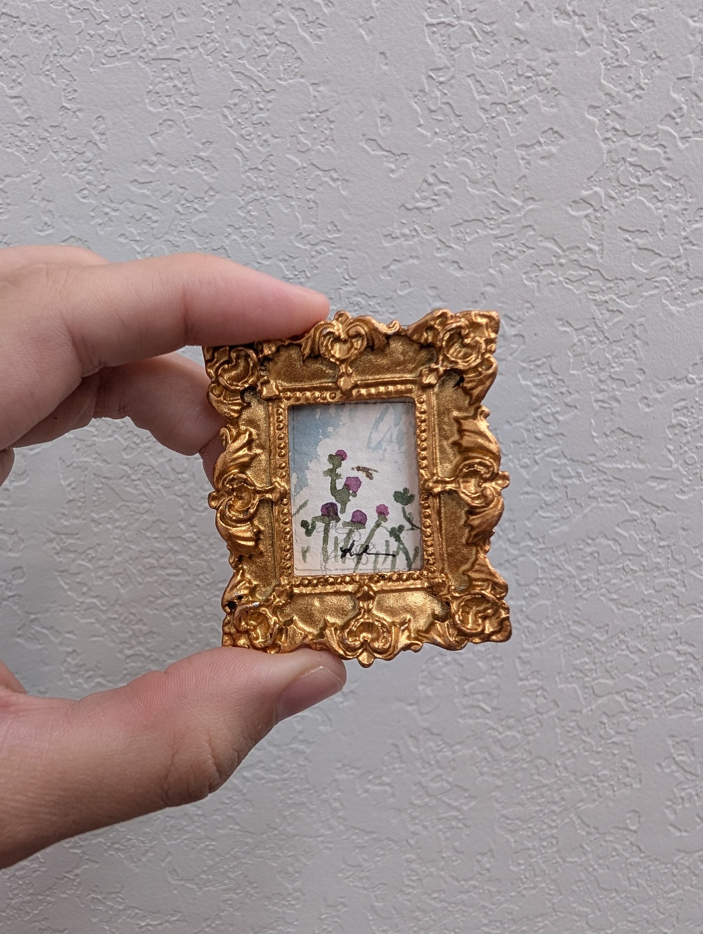a person holding a small picture frame with flowers on it