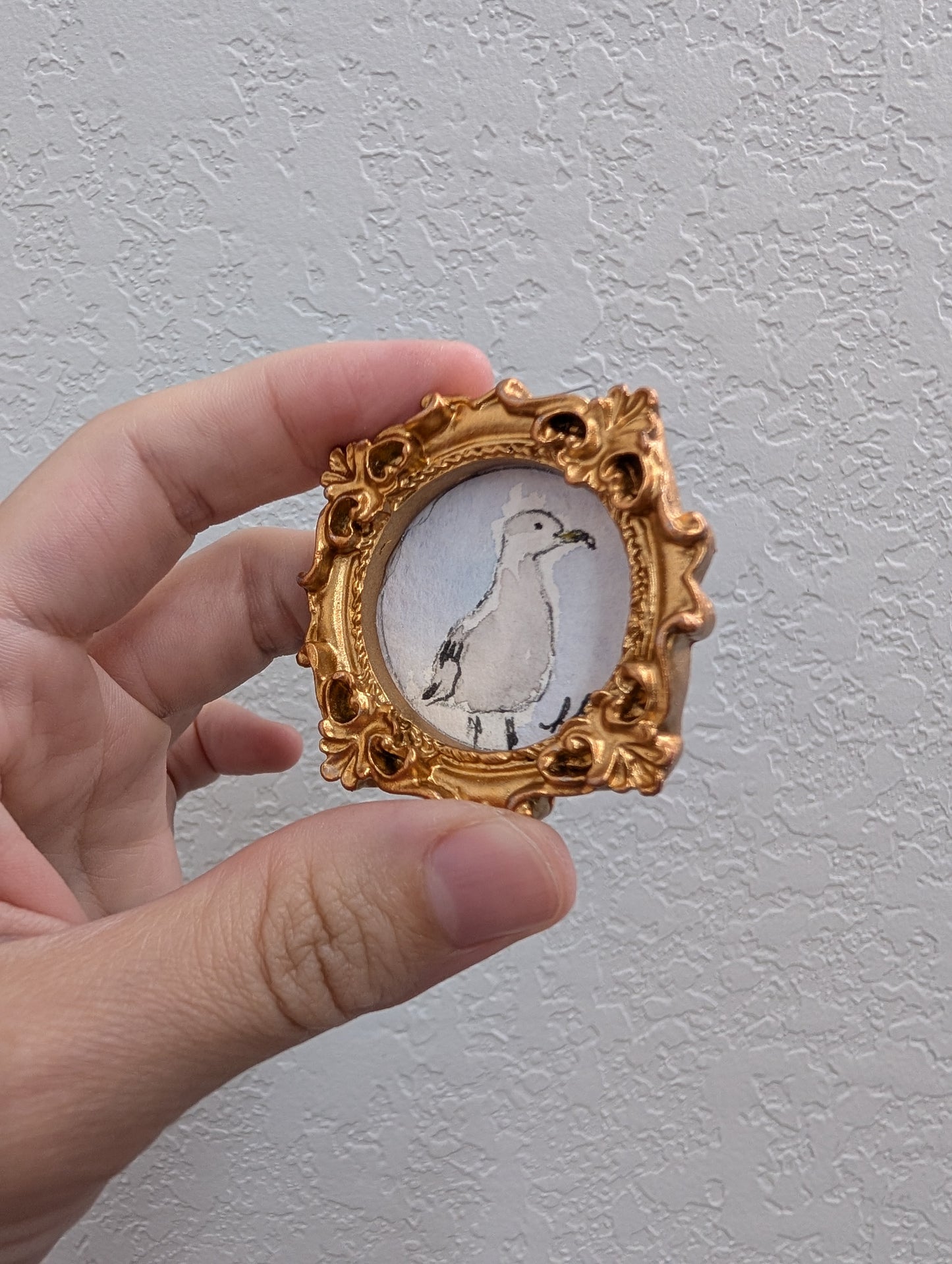 a hand holding a miniature picture of a bird