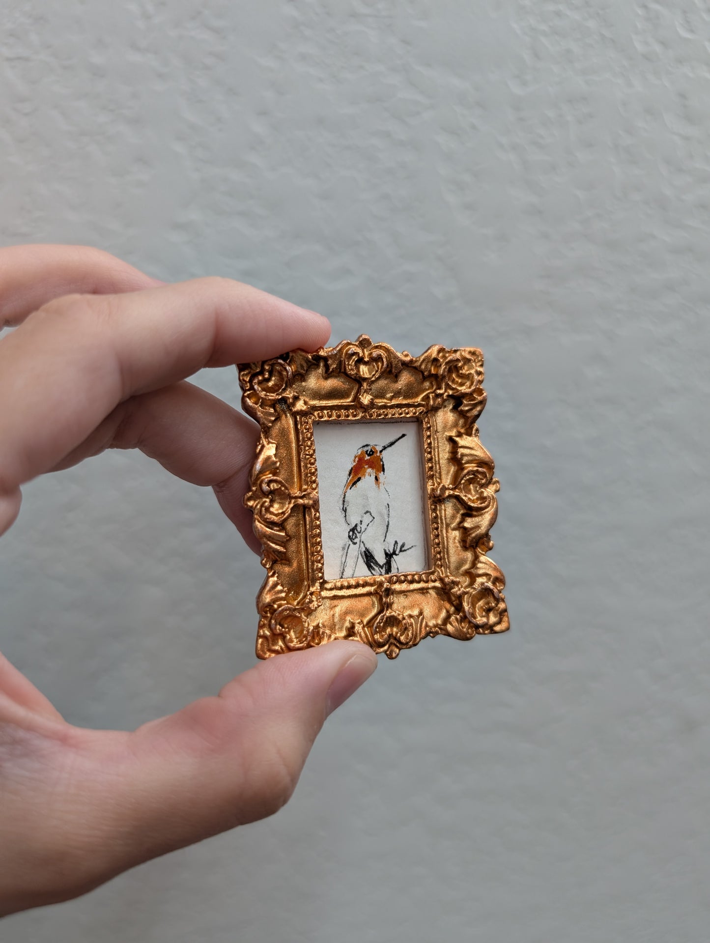 a person holding a small picture frame with a picture of a bird in it
