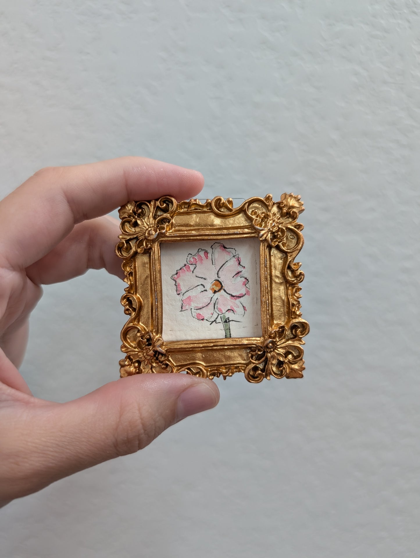 a person holding a small picture frame with a flower on it