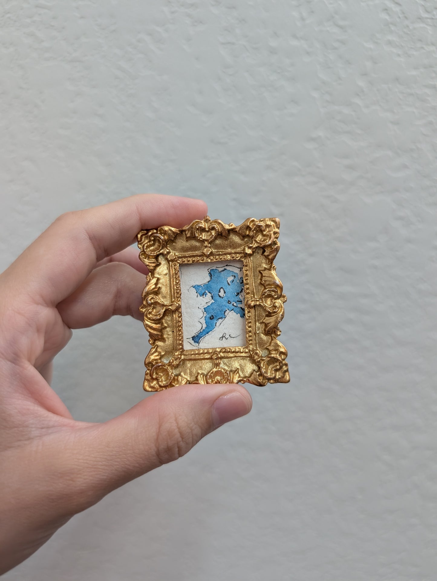 a hand holding a small picture frame with a picture in it