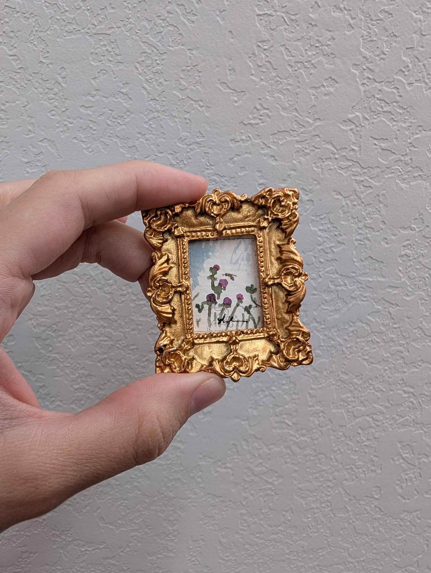 a person holding a small picture frame with flowers on it