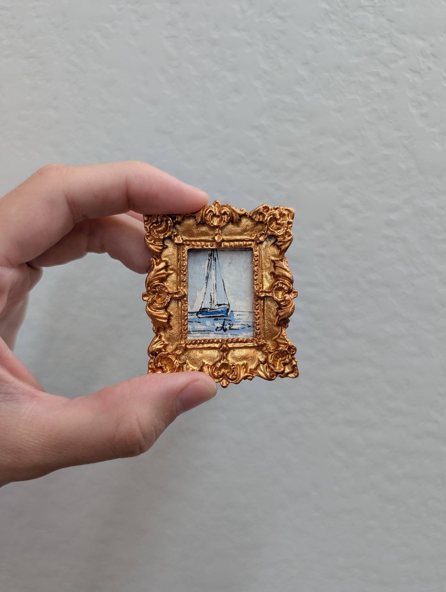 a person holding a small picture frame with a boat on it