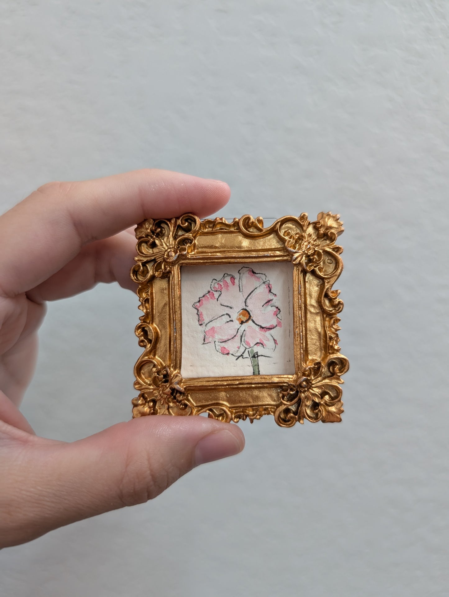 a person holding a small picture frame with a flower on it