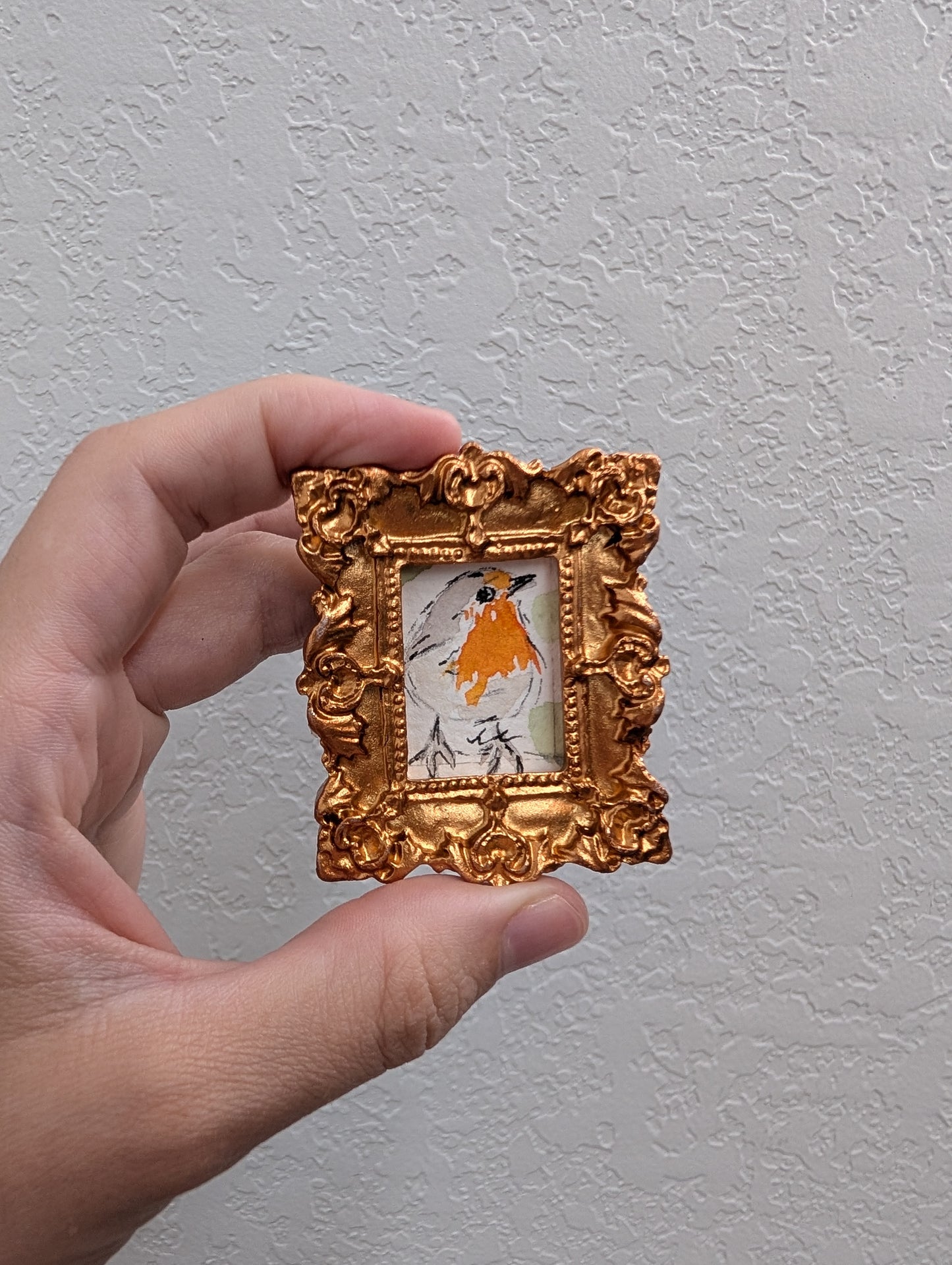 a hand holding a small gold frame with a picture of a horse
