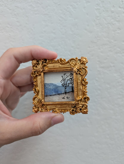 a person holding a small picture frame with a painting on it