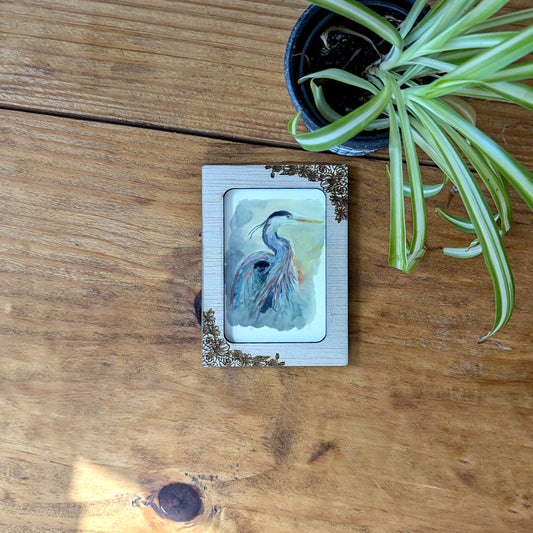 a picture of a bird on a wooden table next to a potted plant