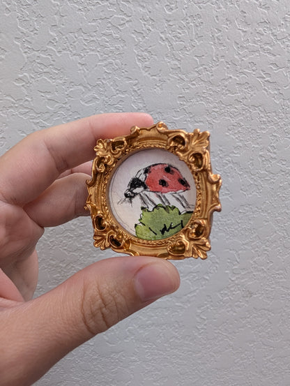 a picture of a ladybug in a gold frame