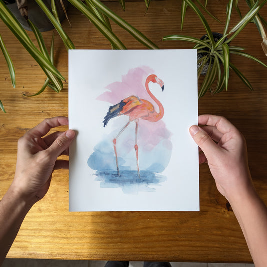 a person holding a card with a watercolor painting of a flamingo