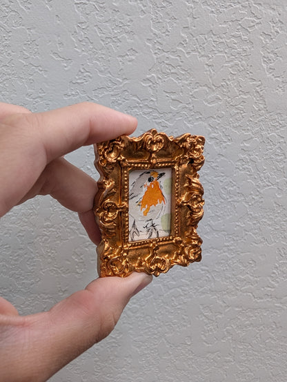 a hand holding a small picture frame with a picture of a woman