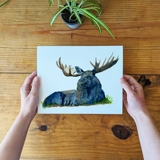 a person holding up a card with a picture of a moose