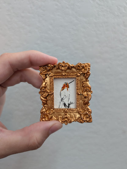 a person holding a small picture frame with a bird on it