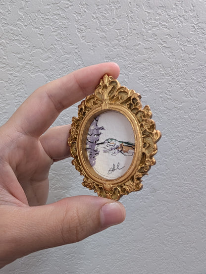 a hand holding a miniature picture of a bird