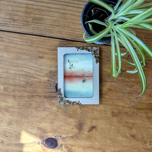 a picture frame sitting on top of a wooden table next to a potted plant