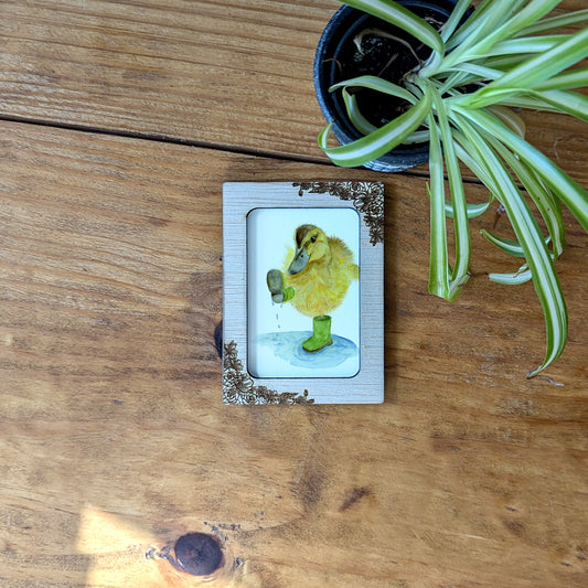 a picture of a small yellow bird on a wooden table