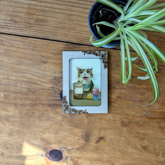 a picture of a cat sitting on a table next to a potted plant