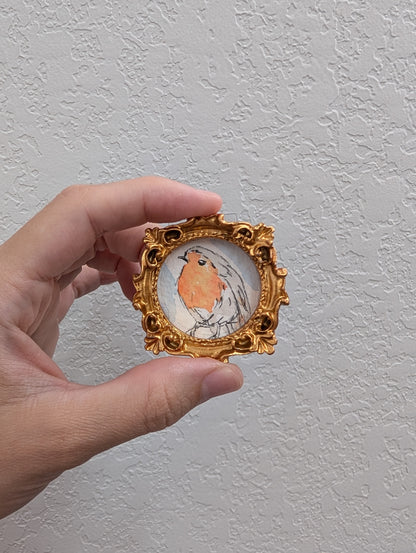 a hand holding a miniature picture of a bird