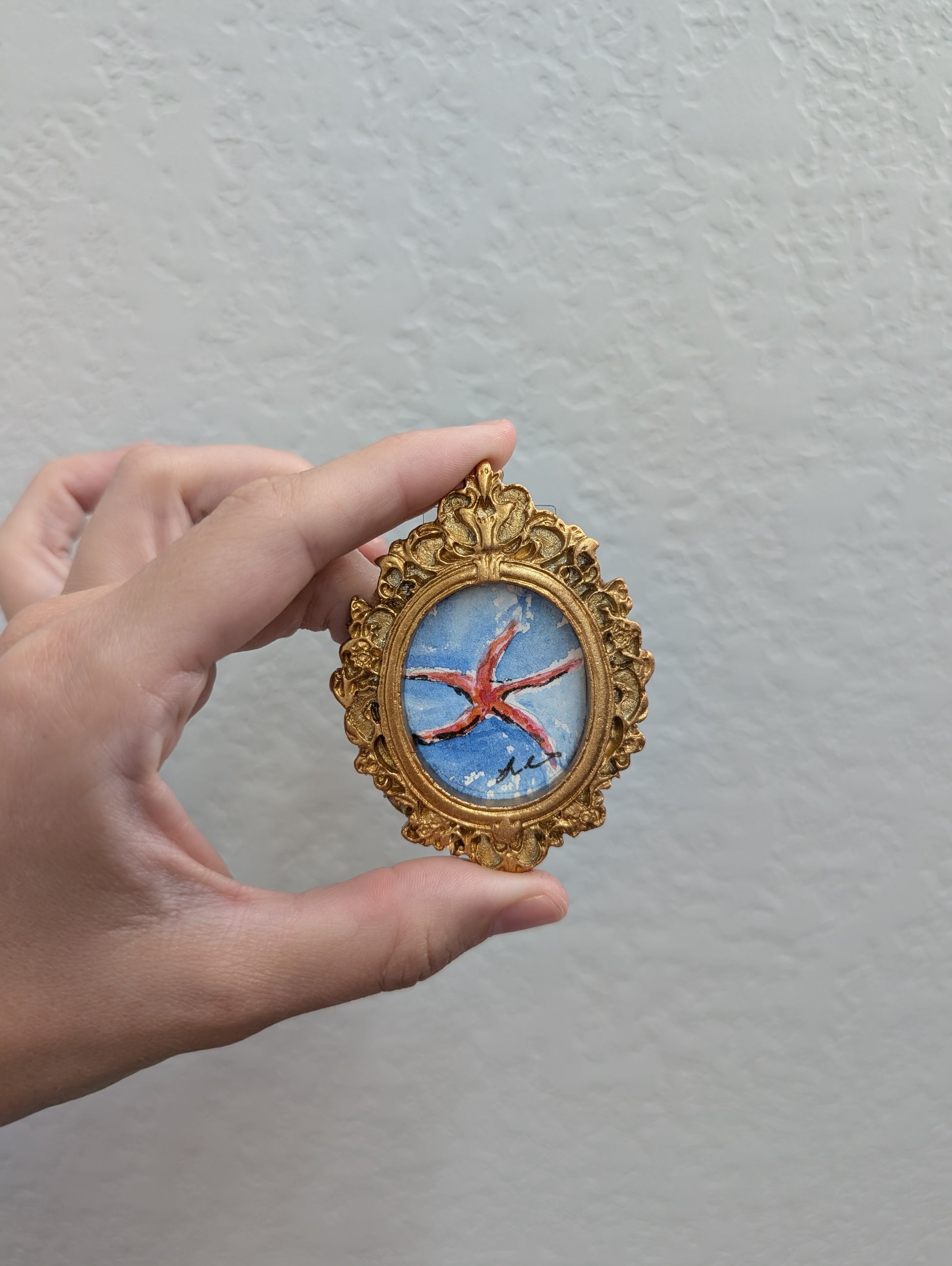 a hand holding a miniature picture of a starfish