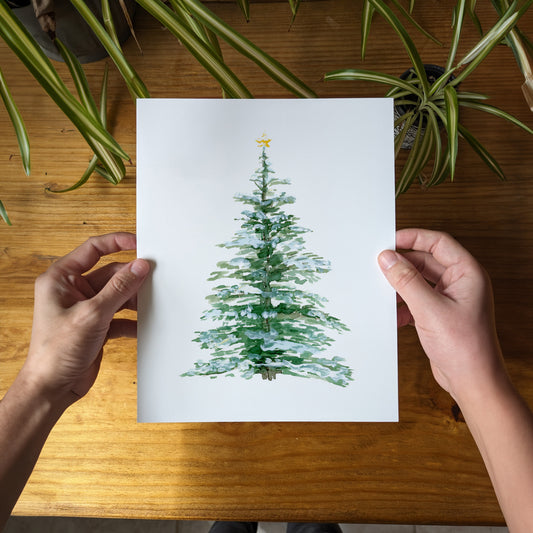 a person holding a card with a christmas tree on it