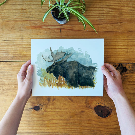 a person holding up a card with a picture of a moose