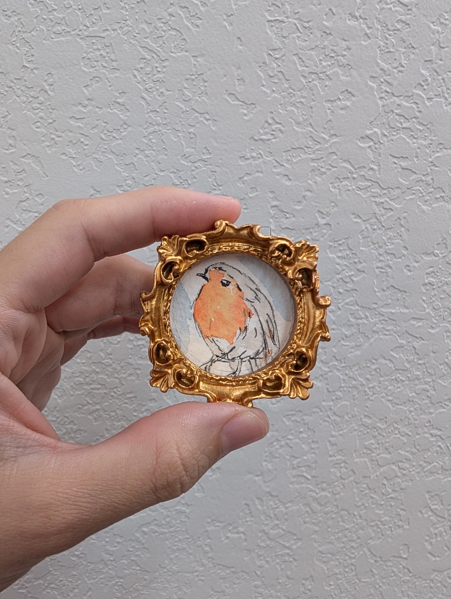 a hand holding a miniature picture of a bird